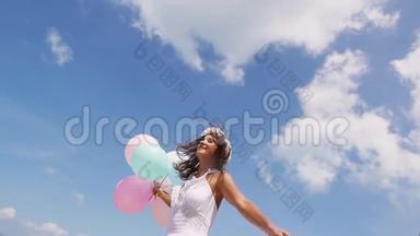 底部的欢乐女孩在海滩上奔跑，<strong>手拿气球</strong>在蓝天背景上。 慢动作
